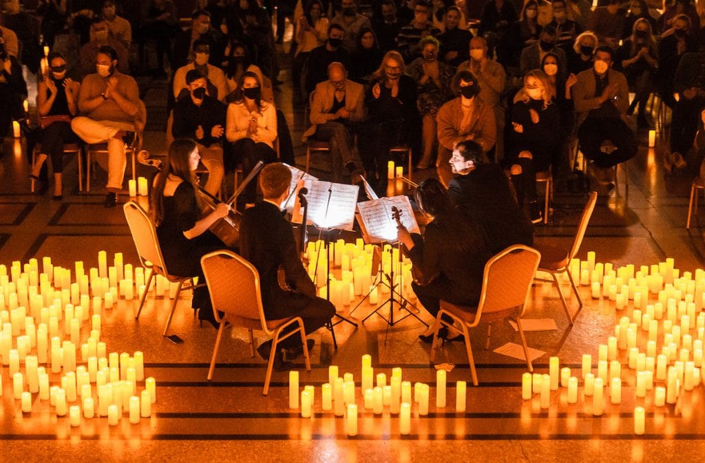 string quartet perform among candlelight in front of a crowd