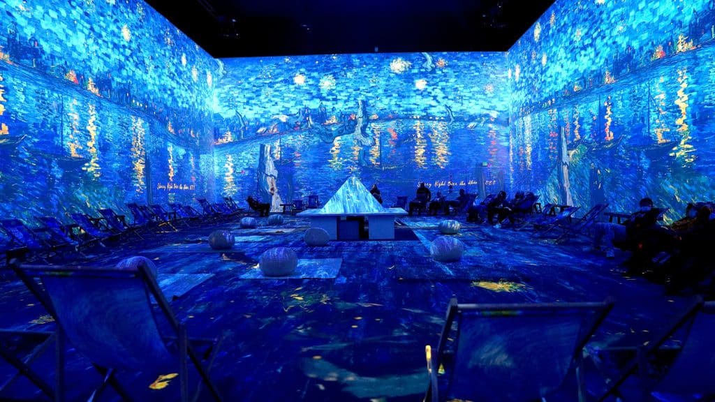 A group of people sat at the edges of the immersive room at Van Gogh: The Immersive Experience