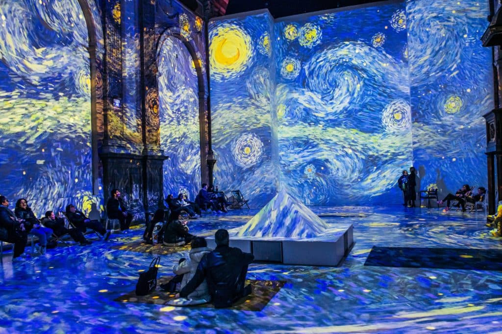 A group of people sat in the immersive room at Van Gogh: The Immersive Experience