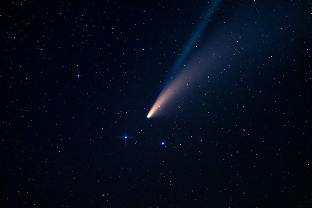 A comet in the night sky, surrounded by stars.