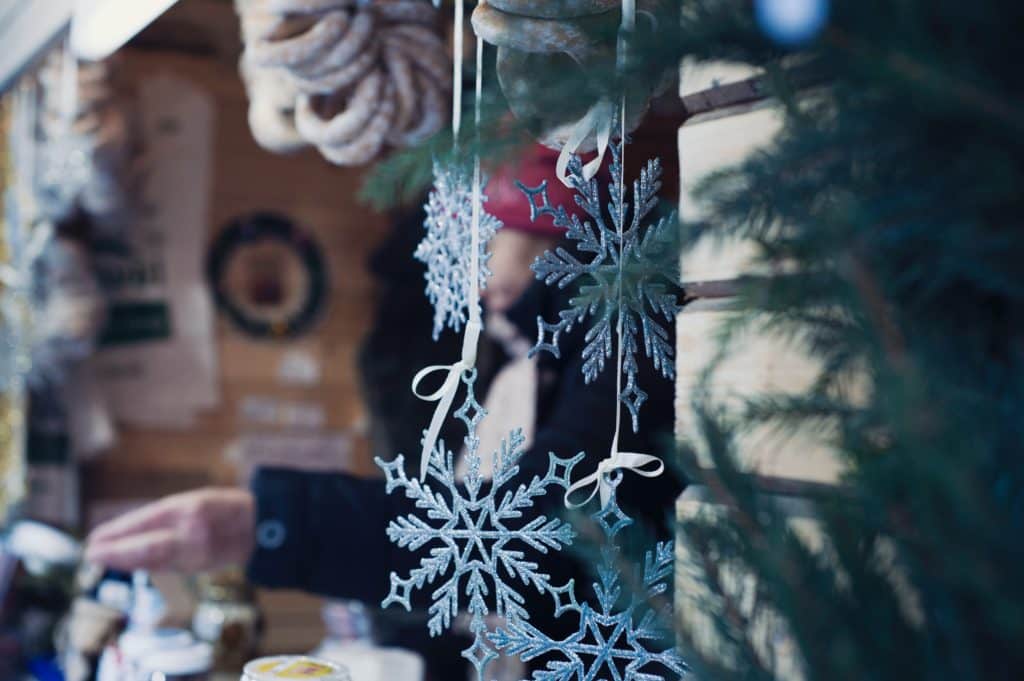 Christmas decorations in the shape of snowflakes hang from a stall at a Christmas market.