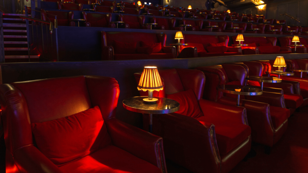 Photo of the interior at Stella Cinemas including plush red seating and a vintage lamp.