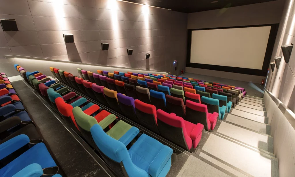 View from the back of a movie theatre at Light House cinema in Dublin showing multi-coloured seats and big screen in the background.