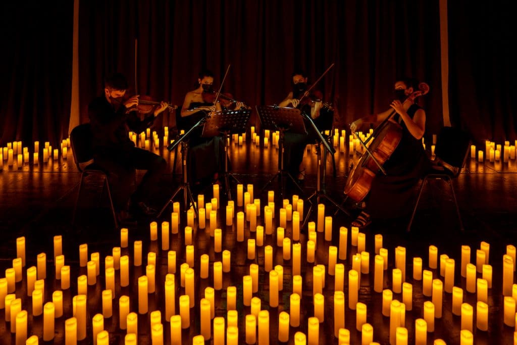 A string quartet perform, surrounded by candles. 