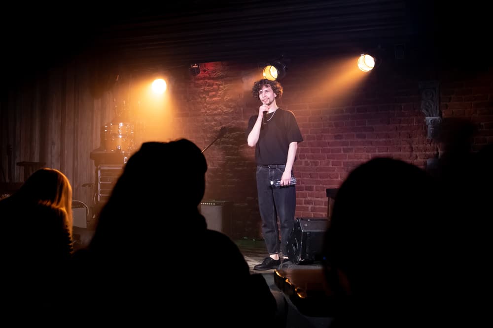A man performs in front of an audience at a comedy club. 