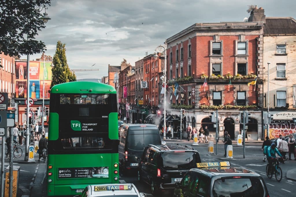 A green Transport for Ireland bus drives through Dublin city centre.