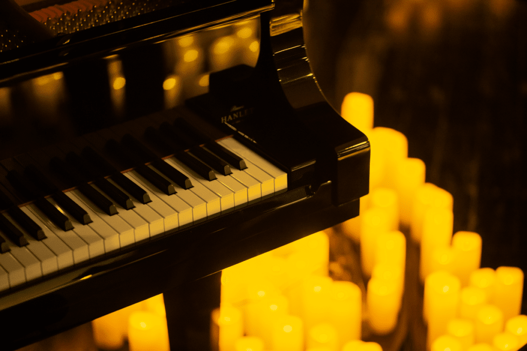A close up of a black grand piano with candles surrounding it